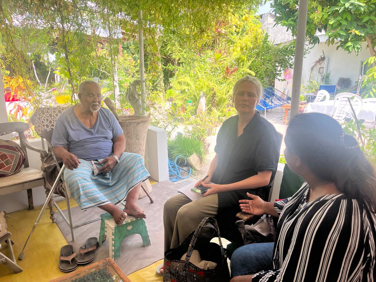 Guest in conversation with Adil's father in the garden waiting area at Carpaccio